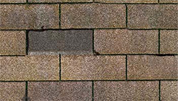 missing roofing shingles from wind damage, brown three tab roofing shingles